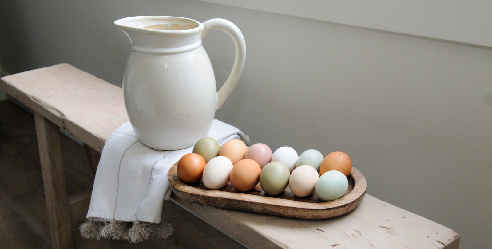 A dozen colorful eggs on a bench.