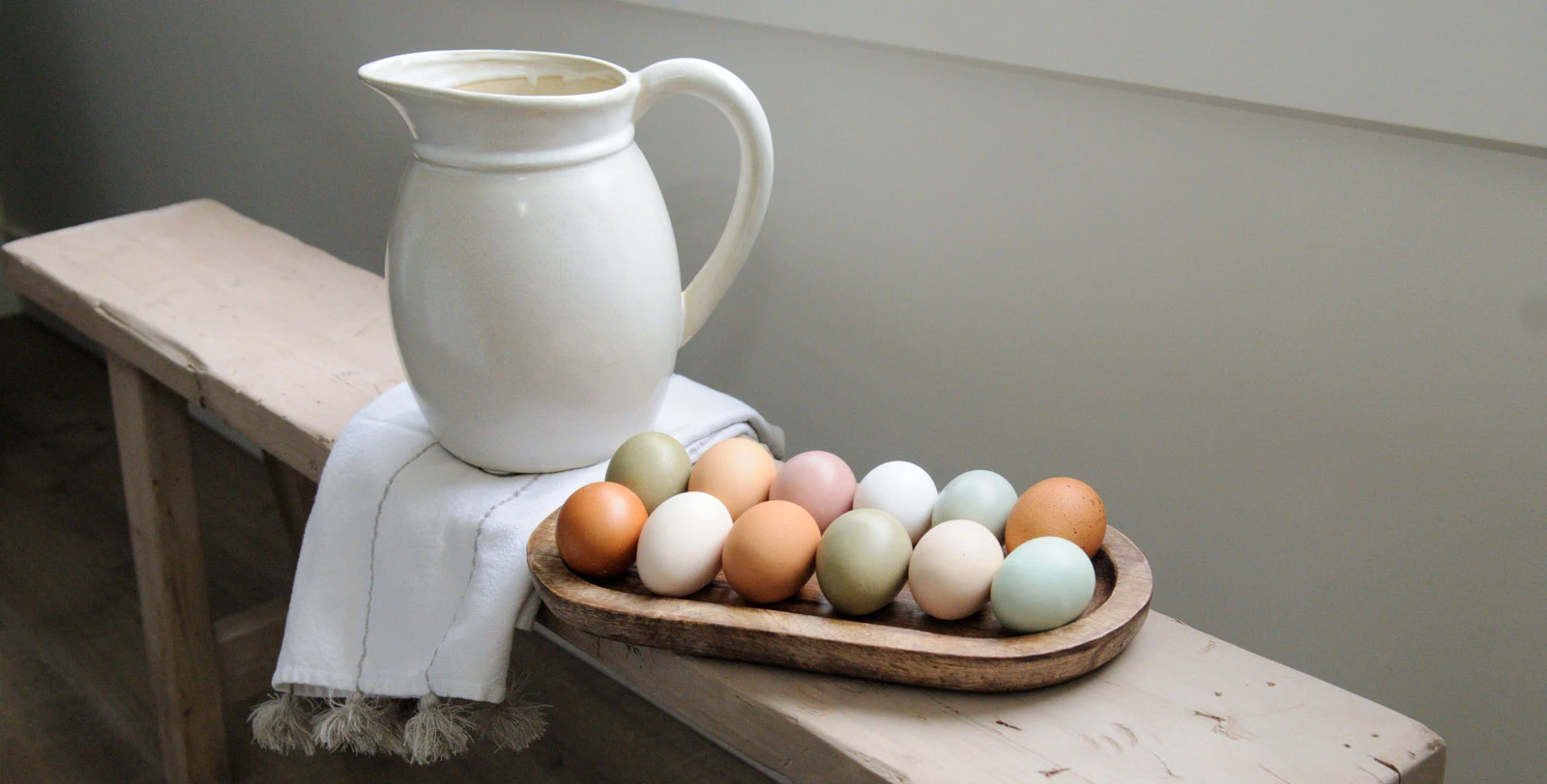 A dozen colorful eggs on a bench.